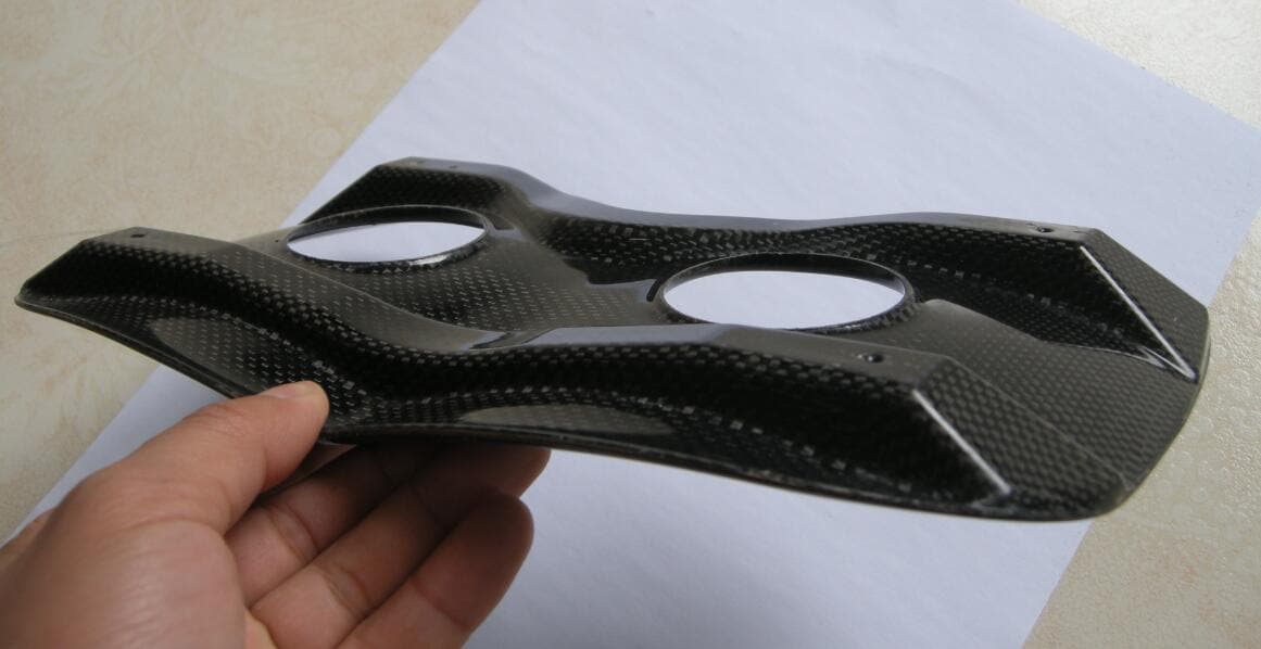 A hand grips a black, textured carbon fiber component, similar to ZJ SPORTs High Quality Carbon Fiber Seat Top Pad for Racing Rowing Boats, with two circular cutouts atop a white sheet. The glossy surface suggests it is lightweight yet durable, ideal for rowing. Free shipping included.