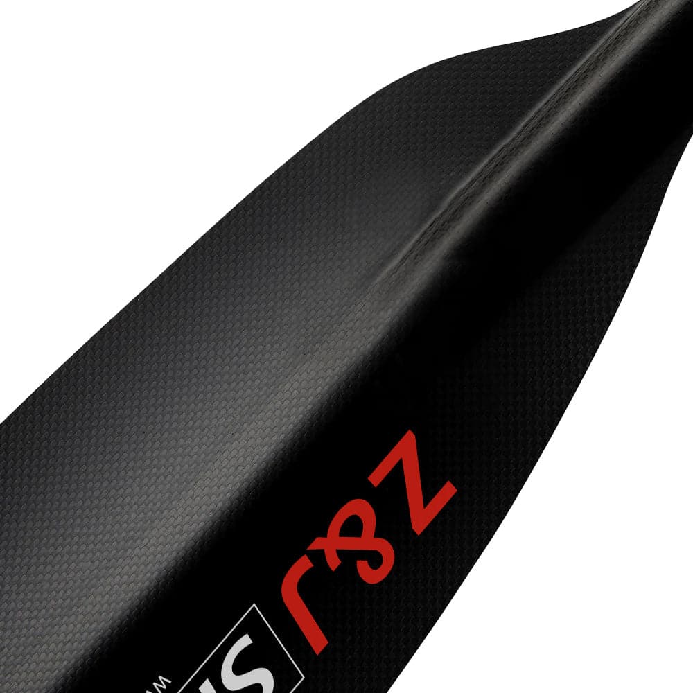 A close-up of the asymmetrical, textured carbon fiber blade from the ZJ SPORT SKR-III paddle features orange and white Ζ and S logos. The diagonally positioned blade reveals part of the shaft, perfect for long-distance paddling.