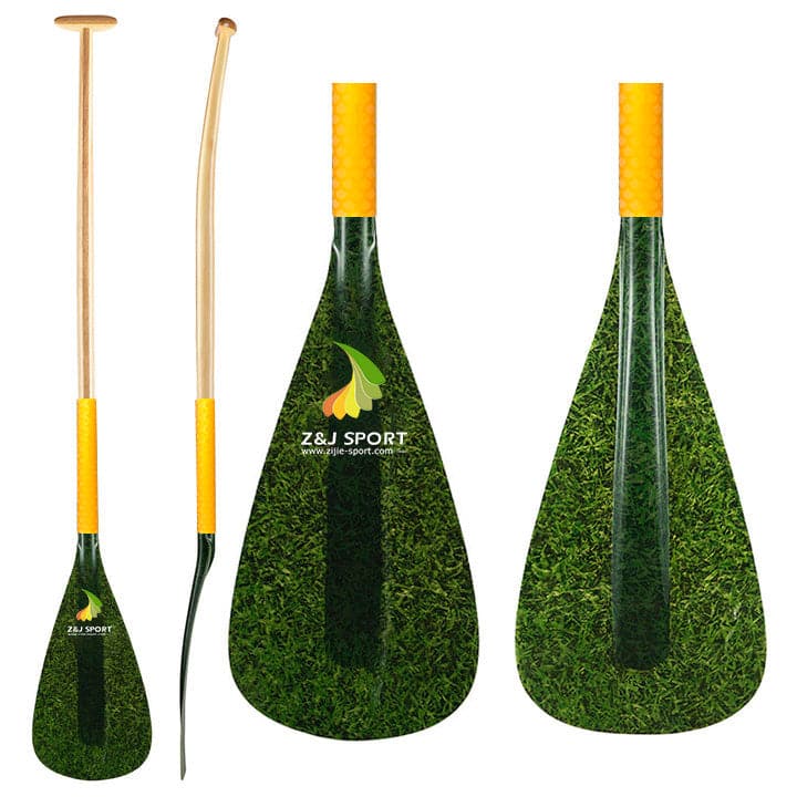 Showcased are three paddles: two have wooden, yellow ergonomic grips—one is straight, one slightly curved. The third features fiberglass blades with a green leaf design and the ZJ SPORT logo from the ZJ Hybrid Outrigger Canoe Paddle for kids, featuring a wood shaft and antiskid grip wrap.