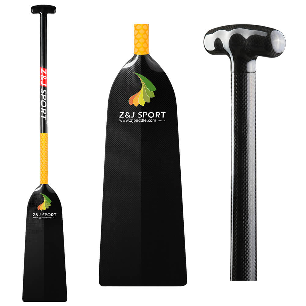 The ZJ SPORT STORM dragon boat paddle features a black carbon fiber blade with a T-shaped handle, adorned with the Z&J SPORT logo and website. This IDBF-approved paddle has a glossy finish and vibrant yellow-orange accents near the top of its dihedral blade for anti-skid grip.