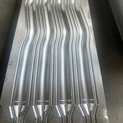 Close-up of a metallic mold crafted through 5 Axis CNC Machining, featuring wavy, parallel grooves that reflect light. The shining surface and precise grooves indicate its industrial use. This specialized mold development is branded as Mold Design (OEM Service) by zijie.