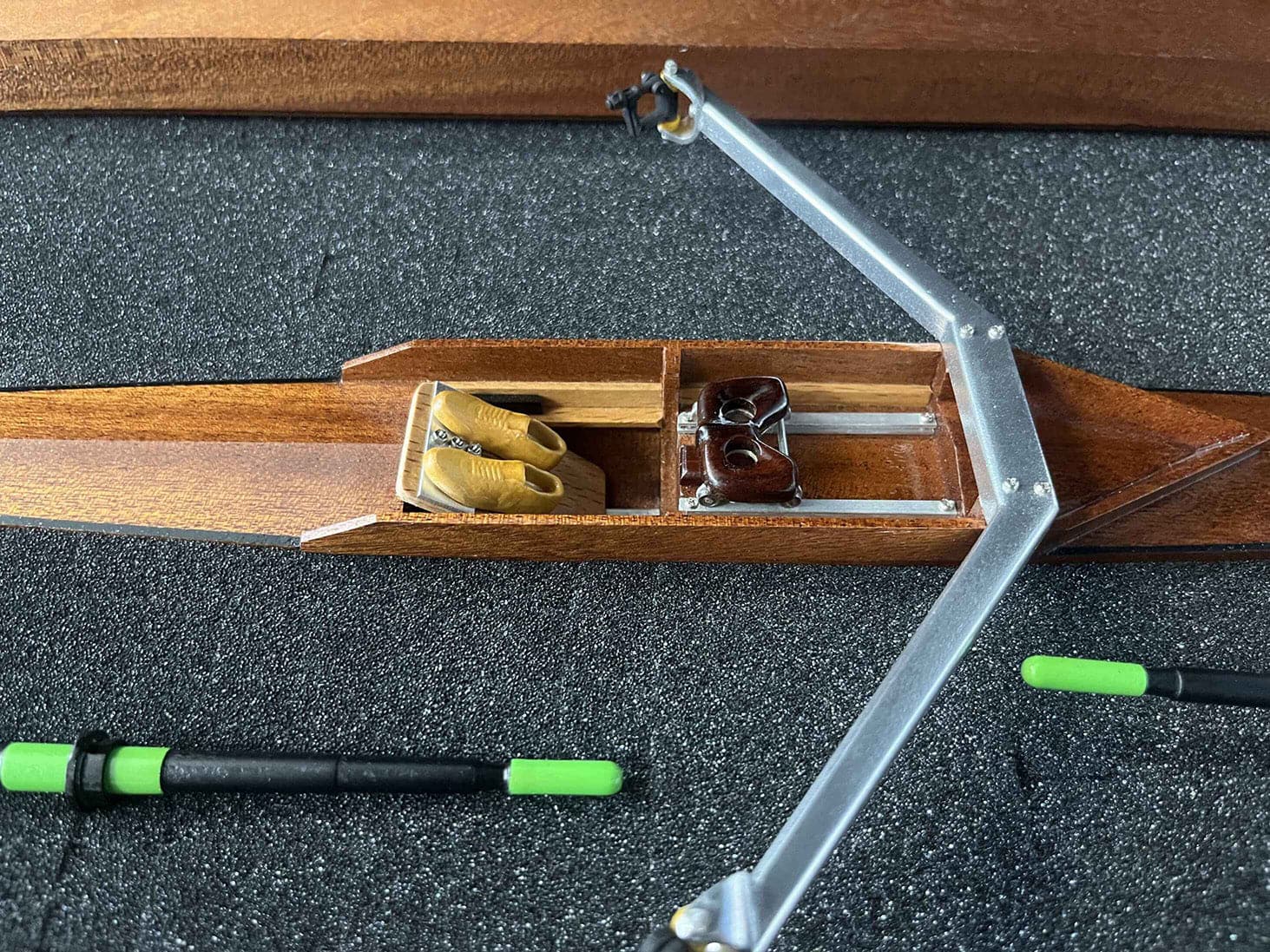 The ZJ Handcrafted Wooden Rowing Boat Model by zijie resembles classic canoes with two detailed seats and footrests. It includes oars with green handles, all presented on a black, textured surface.