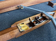 Close-up of the ZJ Handcrafted Wooden Rowing Boat Model by zijie, featuring two rowing shoes, a seat, and rigging components on a black foam backdrop, all beautifully crafted like those in canoes and kayaks.