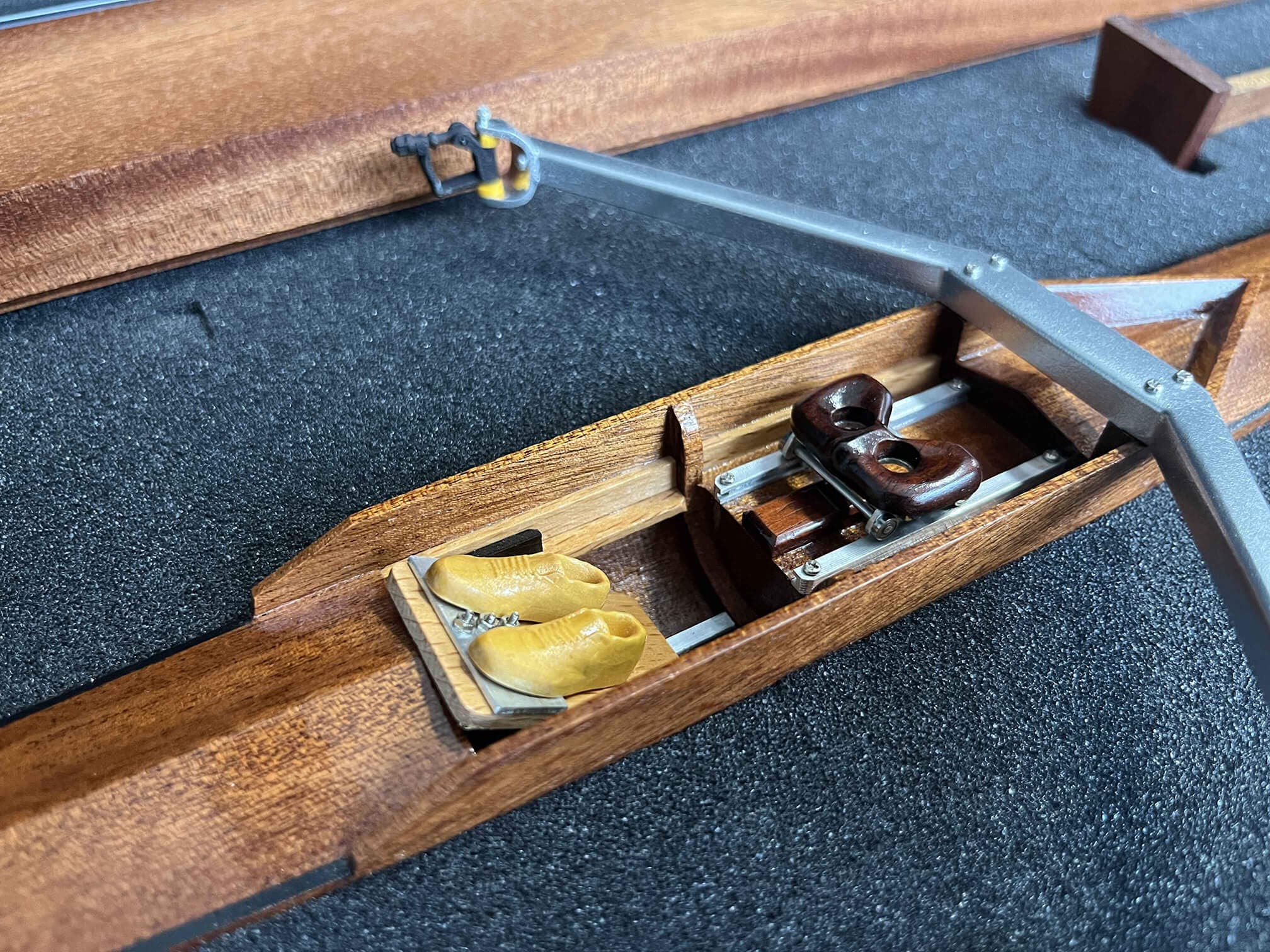 Close-up of the ZJ Handcrafted Wooden Rowing Boat Model by zijie, featuring two rowing shoes, a seat, and rigging components on a black foam backdrop, all beautifully crafted like those in canoes and kayaks.